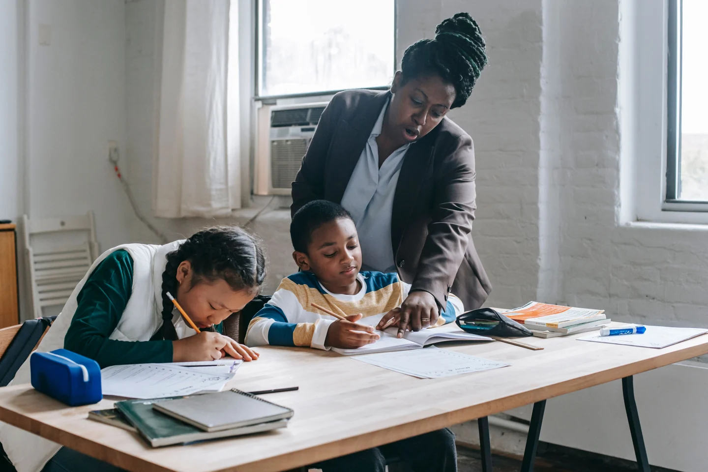 A teacher offering individual encouragement as two children work in a classroom